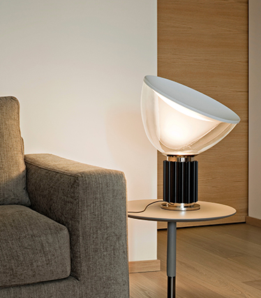 Samtida designlampa som sprider mjukt omgivningsljus bredvid en modern soffa