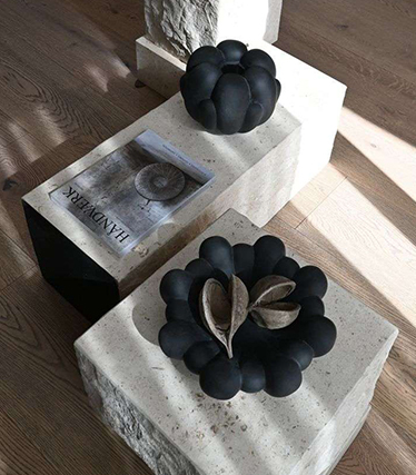 Konstnärliga svarta keramikskålar utställda på minimalistiska stenbord med naturliga texturer