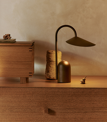 Elegant bordslampa med skulptural design på en träsideboard i mjukt omgivningsljus