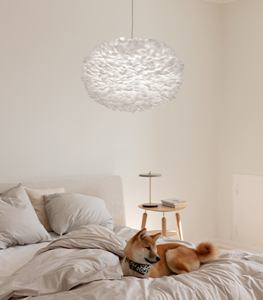 Fluffig pendellampa som skapar en varm och avslappnad atmosfär i ett modernt sovrum med en hund som vilar på sängen
