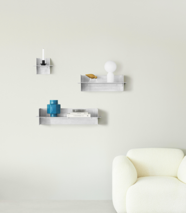 Transparenta Normann Copenhagen vägghyllor med dekorativa accessoarer i ett minimalistiskt vardagsrum.