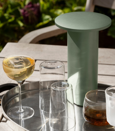 Salviagrönt cylindriskt sidobord/kylare på en bricka med glas och drycker utomhus.